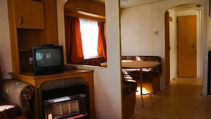 A compact RV interior with a television, a small seating area, and a kitchenette. - Dutch House in Łazy near Lake Jamno (Łazy)