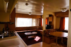 A compact RV interior with a kitchenette, a dining area, and a seating space.