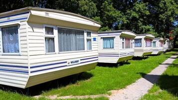 A row of mobile homes with a similar design, featuring a flat roof and a single-story structure.