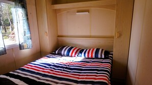 A small, cozy room with a single bed, striped bedding, and a window with a view of the outside. - Dutch House in Łazy near Lake Jamno (Łazy)