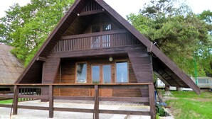 A wooden cabin with a sloped roof, a balcony, and large windows. - Summer House in Łazy by Lake Jamno (Łazy)