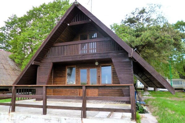 A wooden cabin with a sloped roof, a balcony, and large windows. - Summer House in Łazy by Lake Jamno (Łazy)
