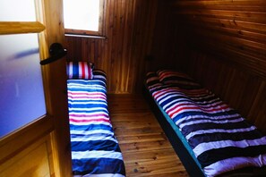 A narrow wooden room with two beds, each with striped bedding. - Summer House in Łazy by Lake Jamno (Łazy)