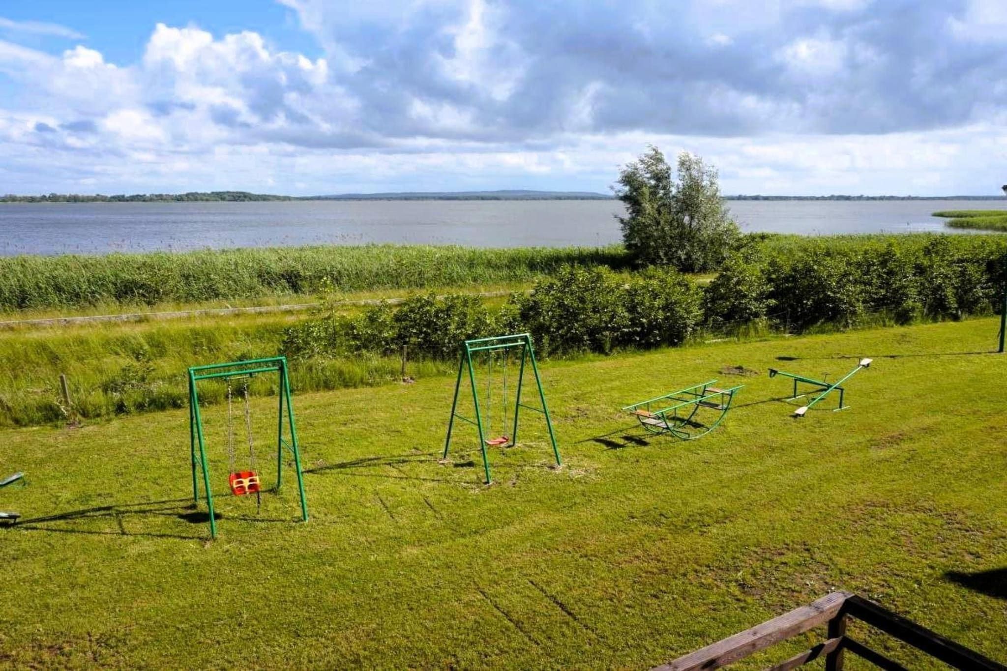Une zone herbeuse avec des balançoires et une clôture en bois.