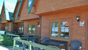 A wooden cabin with multiple rooms, each with a window and a small table.