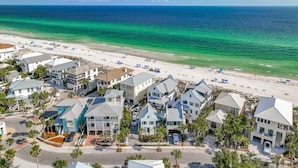 Un quartier résidentiel situé sur la côte, avec des propriétés donnant sur la plage, une eau d’un bleu limpide et une plage de sable.