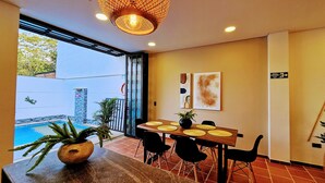 A dining area with a wooden table, black chairs, and a potted plant.