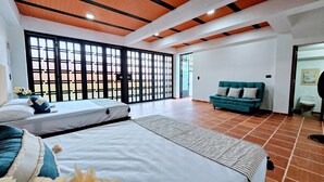 A hotel room with two beds, a sofa, and a large sliding door with a view.