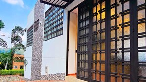 A modern building with a brick-paved courtyard, large windows with black frames, and a stone-textured wall.