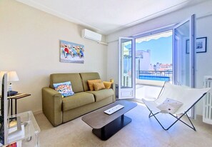 Ein modernes Wohnzimmer mit einer Couch, einem Couchtisch, einem Sessel und einem Gemälde an der Wand.
