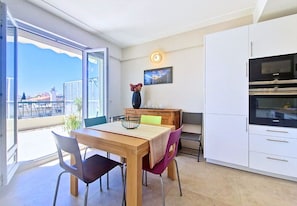 A dining area with a table, chairs, a vase, and a view through a glass door.