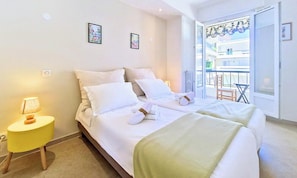A hotel room with a bed, a small table with a lamp, and a view of the outside balcony.