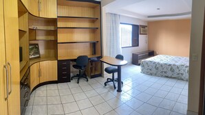 A room with a desk, chair, bed, and built-in shelving. - AMORA SPACES - APARTAMENTO TOP LINHARES (Linhares)