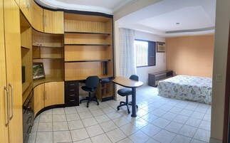 Quarto com escrivaninha, cadeira, cama e prateleiras embutidas.