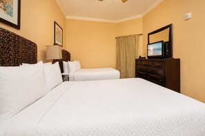 Habitación de hotel con dos camas, un aparador, un televisor y un ventilador de techo.