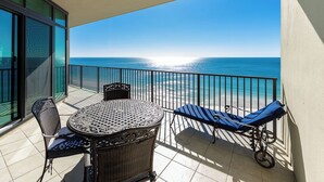 A balcony with a table and chairs, overlooking a beach.