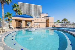 Ein Hotel mit Pool, Palmen und einem großen Gebäude im Hintergrund.