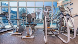 An indoor gym with treadmills, ellipticals, and a pool visible through large windows. - Crystal Tower 1102 - Stunning Condo! (Gulf Shores)