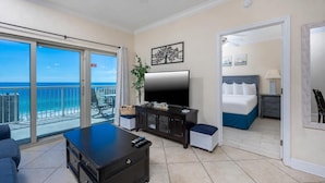 A hotel room with a balcony, a TV, a bed, and a desk. - Crystal Tower 1102 - Stunning Condo! (Gulf Shores)
