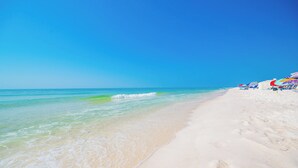 A beach with clear turquoise water, white sand, and colorful umbrellas. - Crystal Tower 1102 - Stunning Condo! (Gulf Shores)