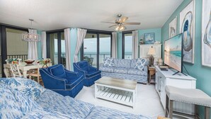 A living room with a sofa, chairs, a coffee table, and artwork on the walls. - Phoenix IV 4025 Beachfront Corner Retreat (Orange Beach)