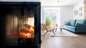 A cozy living room with a fireplace, a sofa, a chair, and a small table. - Soloandie (Zeanuri)