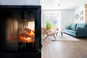Una sala de estar acogedora con chimenea, un sofá, un sillón y una mesita.