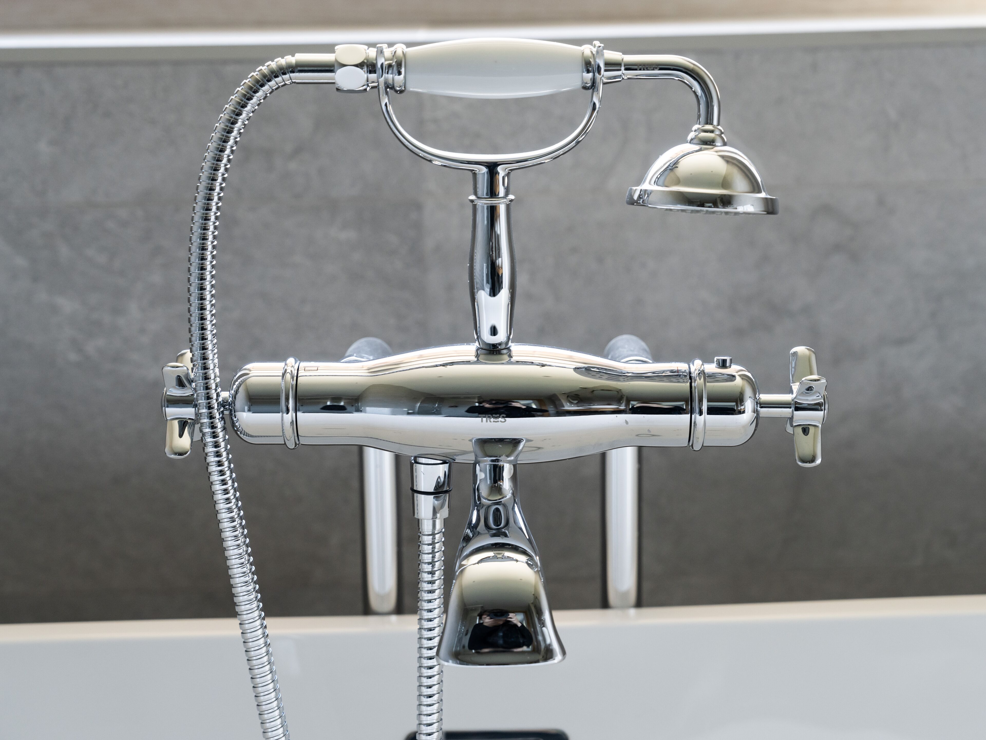 Un accesorio de baño cromado con cabezal de ducha, ducha de mano y llave de dos mandos.