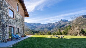 A stone building with a patio, a lawn, and a mountainous landscape in the background. - Soloandie (Zeanuri)