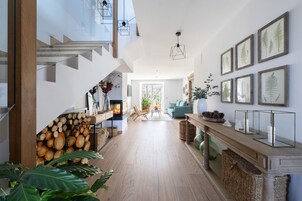 Un interior moderno con una escalera, suelo de madera, zona de comedor e impresiones botánicas enmarcadas en las paredes.
