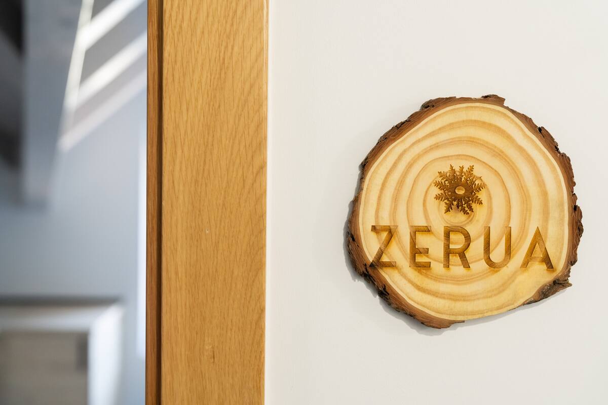 A wooden sign with the word "ZERUA" carved into it, mounted on a white wall.