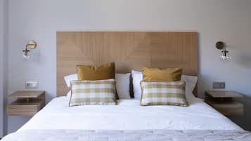 Een netjes opgemaakt bed met een houten hoofdbord, twee nachtkastjes met lampen en een wandlamp.