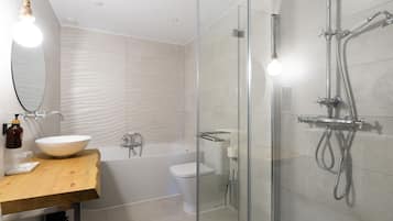 A modern bathroom with a glass-enclosed shower, a wooden vanity, a white sink, and a large mirror.