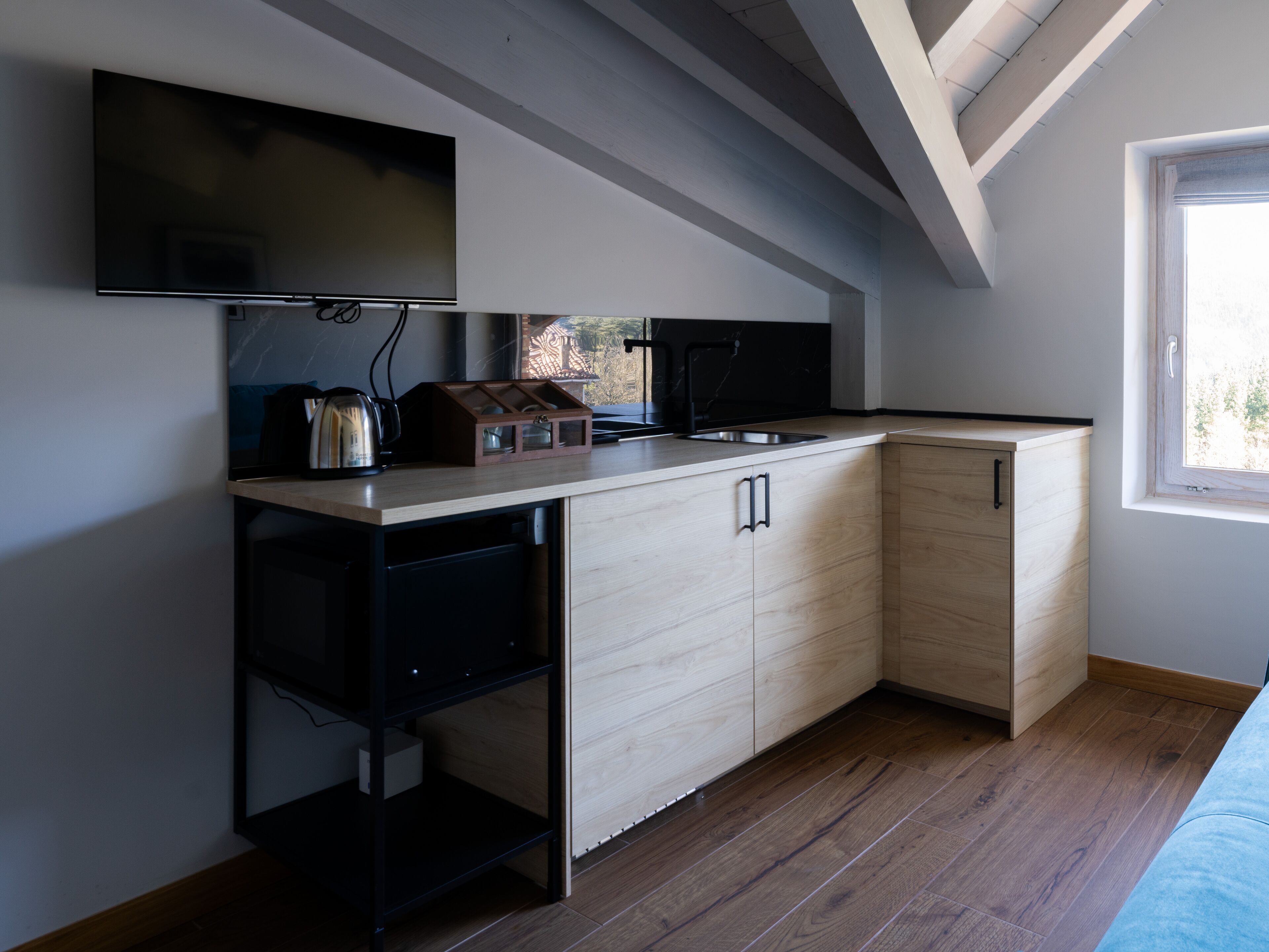 Una cocina compacta con lavavajillas integrado, encimera de madera y ventana que proporciona luz natural.