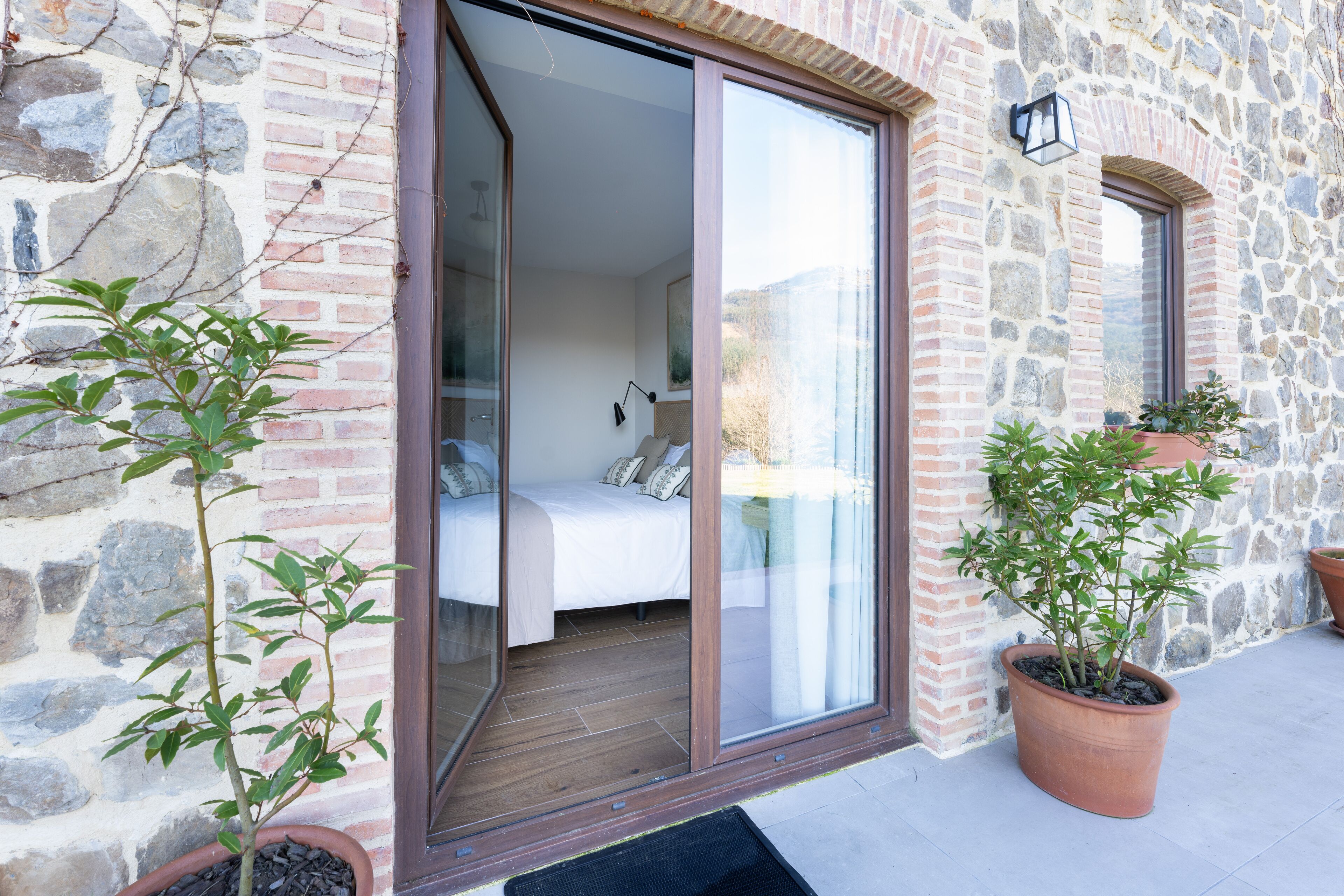 A room with a bed, a sliding glass door, and a stone wall.