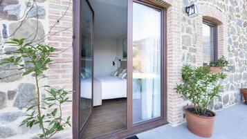 A room with a bed, a sliding glass door, and a stone wall.