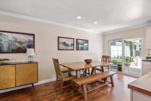 Un coin repas comprenant une table et des chaises en bois, un banc, un buffet orné de panneaux décoratifs et deux tableaux encadrés accrochés au mur.