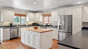 Una cocina moderna con armarios blancos, electrodomésticos de acero inoxidable y una isla central.