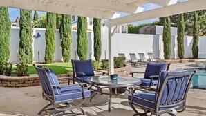 Un patio cubierto con mobiliario exterior y una piscina.