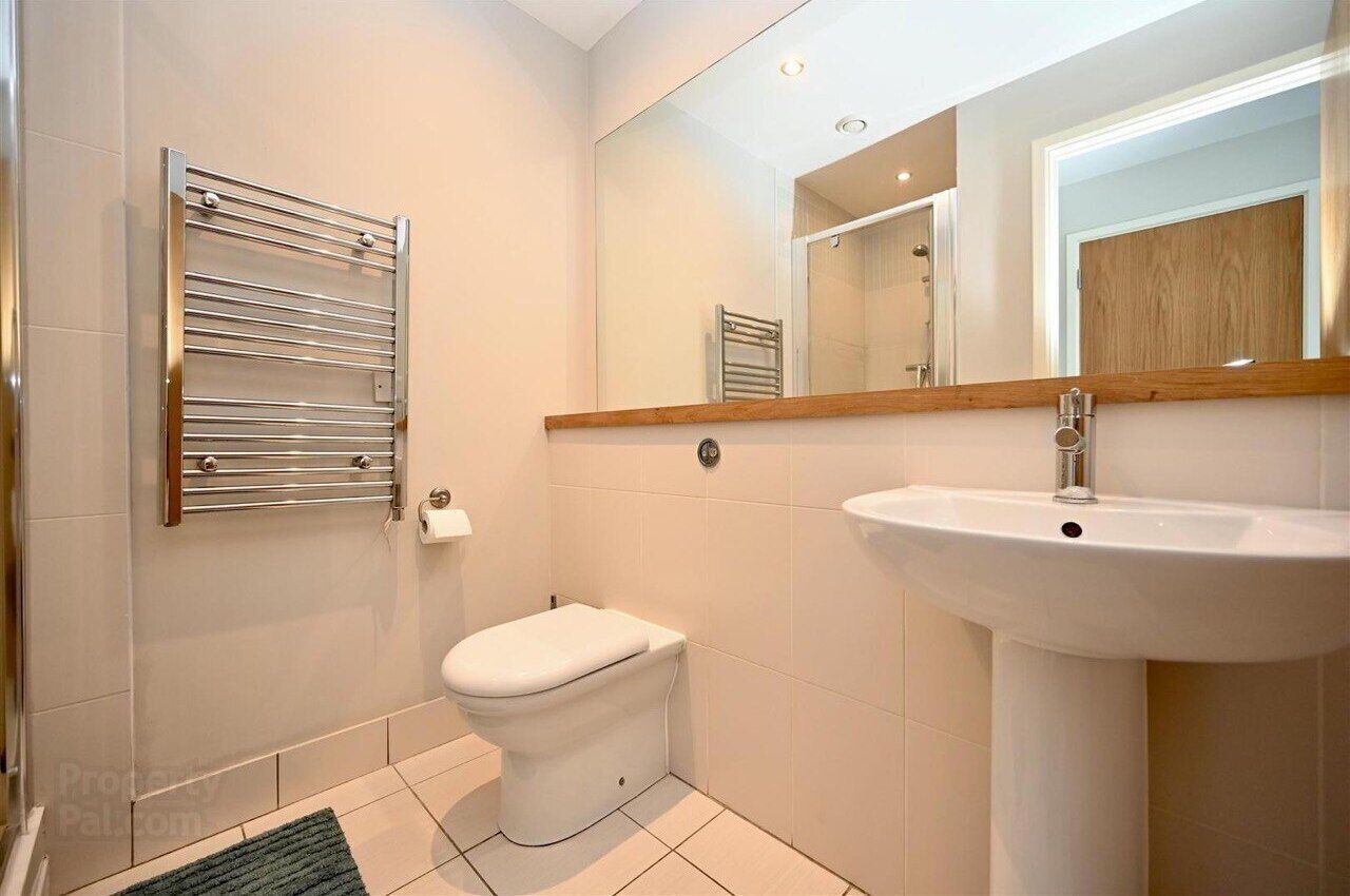 A bathroom with a toilet, a sink, a towel rack, and a mirror.