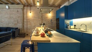 A modern kitchen with blue cabinets, a marble countertop, and a wooden dining table.
