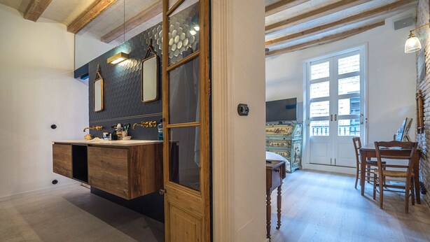 A modern bathroom with a wooden vanity, a large mirror, and a decorative wall.