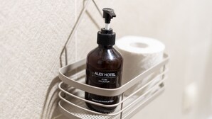 A bathroom with a bottle of shampoo and a roll of toilet paper on a shelf. - Economy Type Rooms (Yerevan)