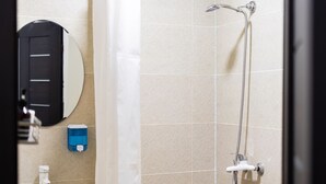 A bathroom with a shower, a sink, a mirror, and a soap dispenser. - Economy Type Rooms (Yerevan)