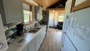 Una cocina con techo de madera, electrodomésticos de acero inoxidable y un refrigerador con un aviso.