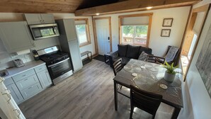 Cocina compacta con electrodomésticos modernos, comedor con mesa y sillas, y zona de estar acogedora con sofá.