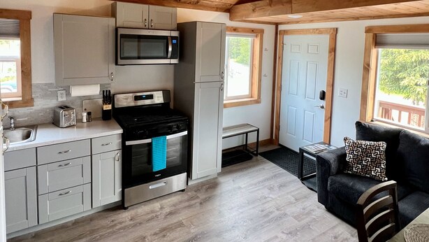 Una cocina amplia con vigas de madera en el techo, un microondas, una estufa y un fregadero. Hay una pequeña zona de estar con un sofá y una mesa.
