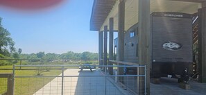 A building with a covered outdoor area, a wooden deck, and a fenced-in grassy area.