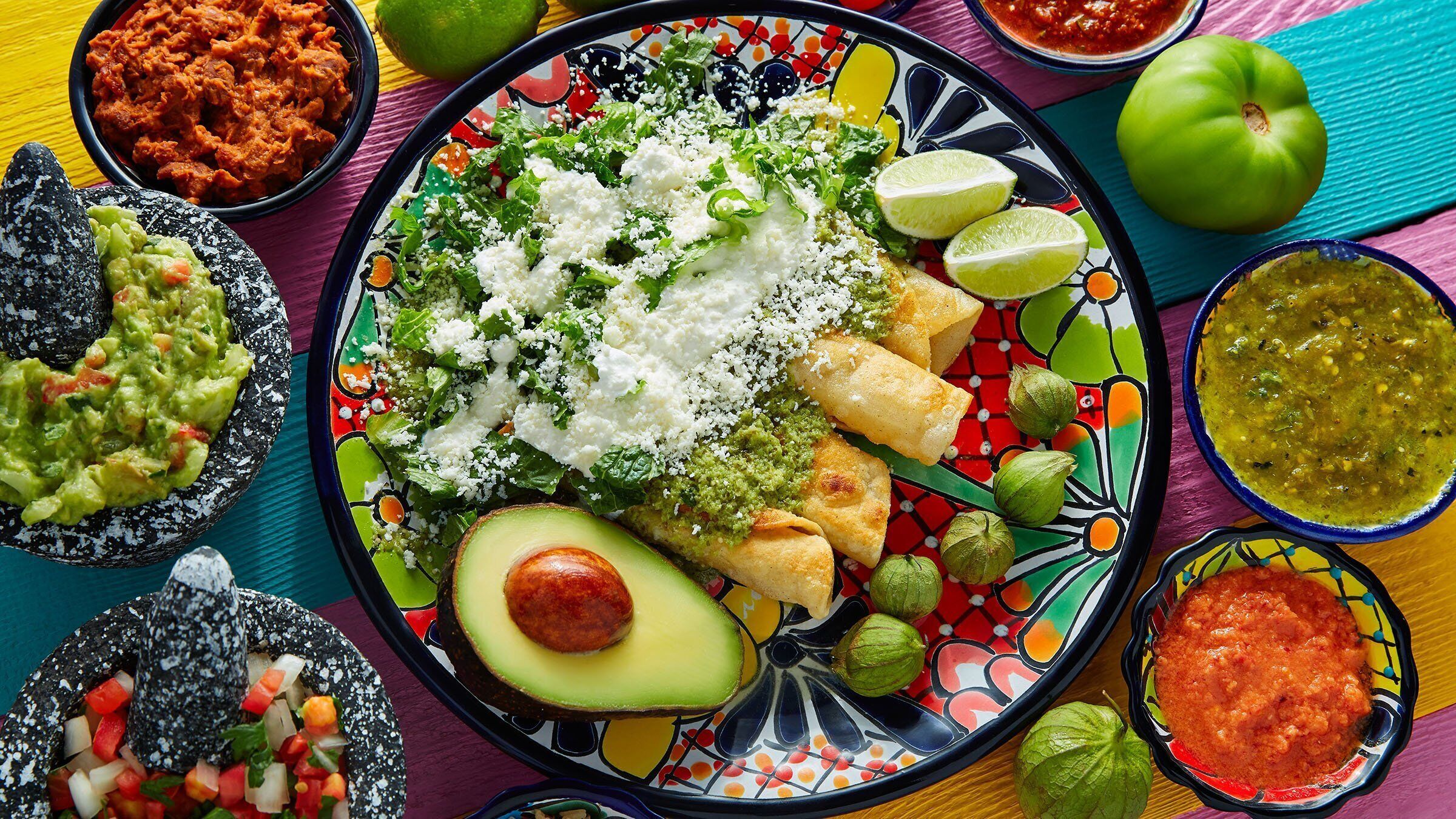 A colorful plate with various Mexican dishes, including tacos, guacamole, and salsa.