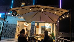 An outdoor seating area with a glass enclosure, a Christmas tree, and a neon sign. - HOTEL VIP 46 SSQS (Bagua Grande)